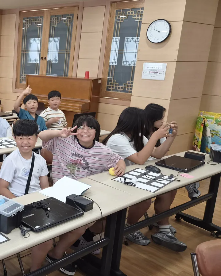 교실 긴 탁자에 모여 앉은 아이들과 청소년들